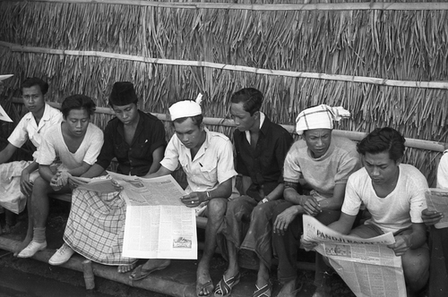 Penghuni sebuah kamp tahanan di Bali sedang membaca koran